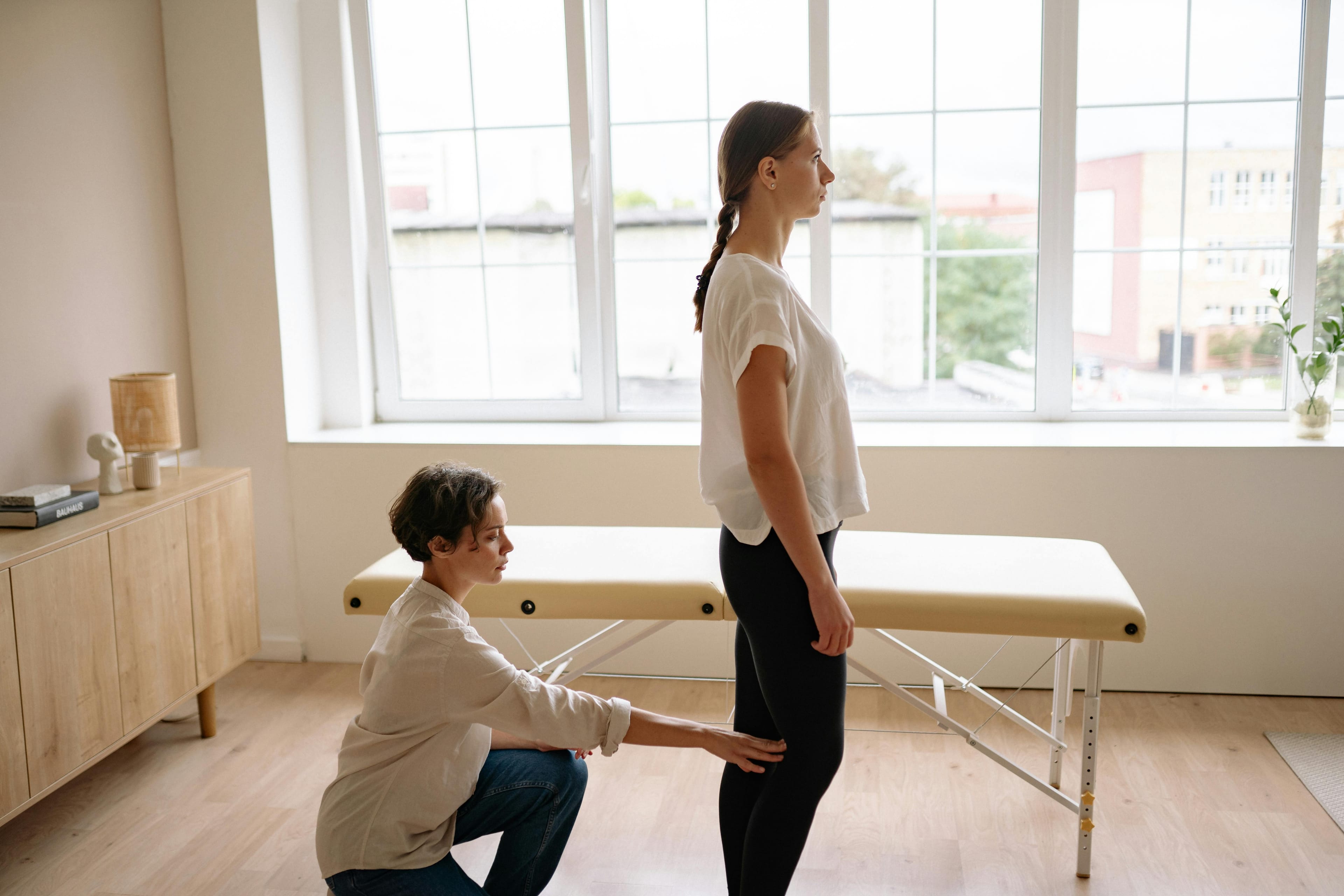 A physiotherapist assessing a client's posture in a bright, modern clinic.