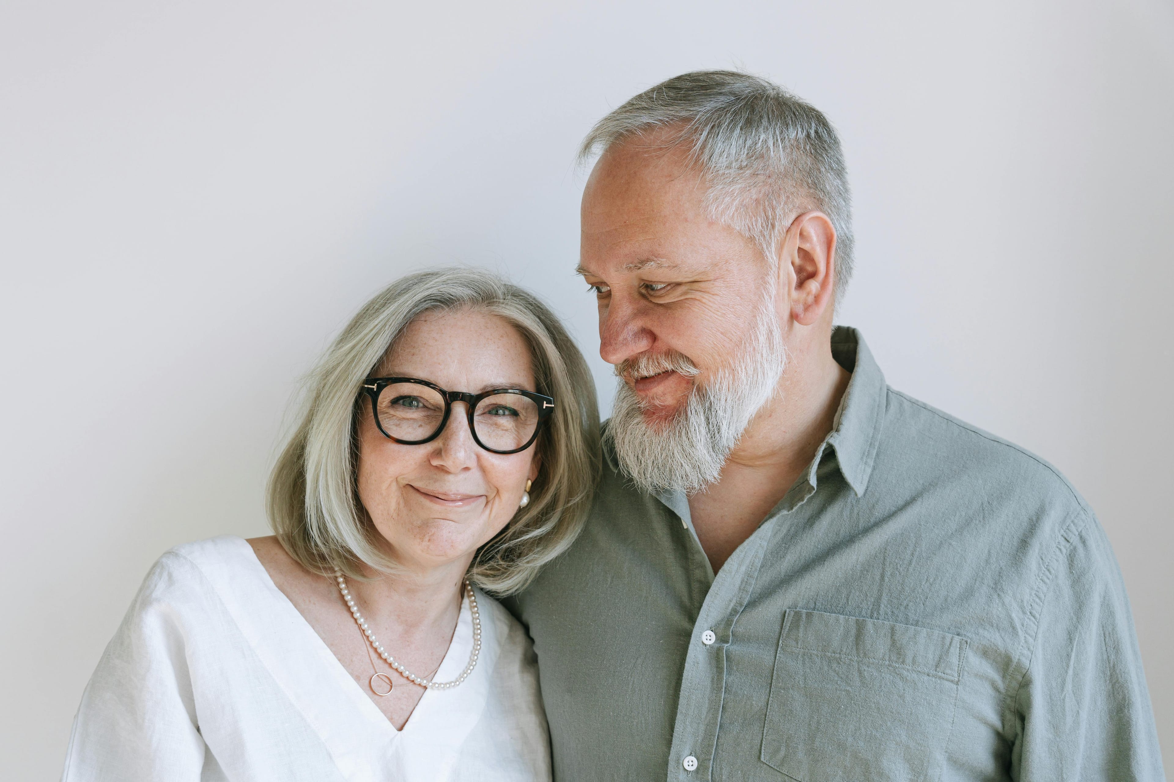 Happy senior couple smiling together indoors, showing warmth and love.